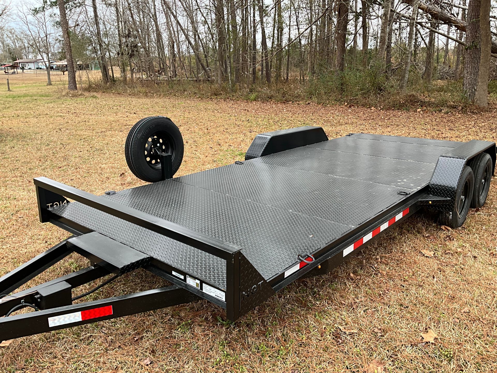 Woman in straw hat smiles, holding wine glass near a lake.