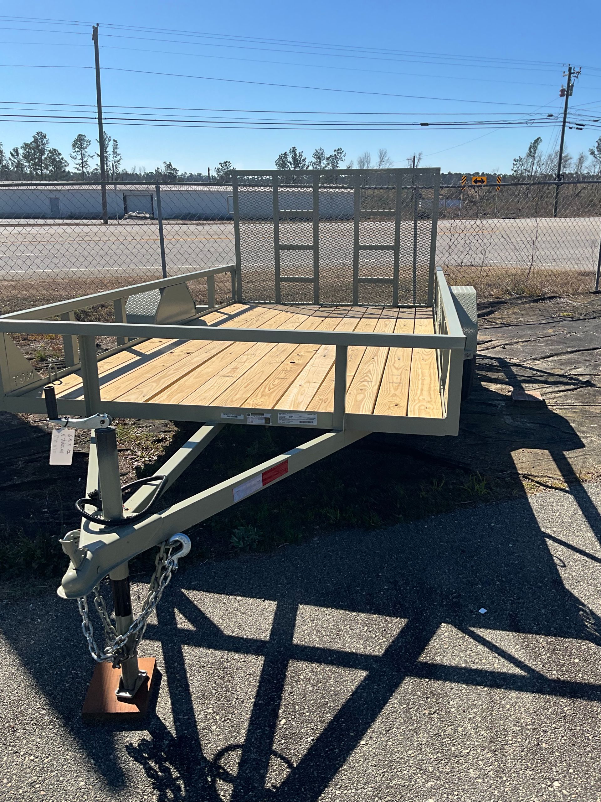 Woman in straw hat smiles, holding wine glass near a lake.