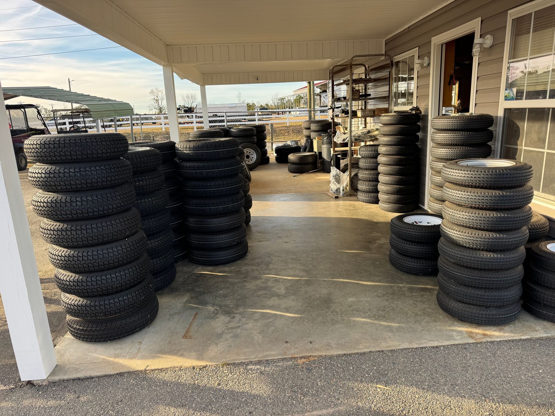 Woman in straw hat smiles, holding wine glass near a lake.