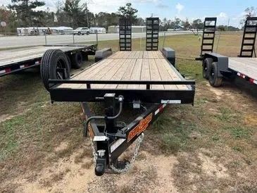 Woman in straw hat smiles, holding wine glass near a lake.