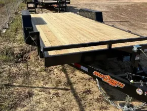 A new black utility trailer with a light-colored wooden deck parked on a dirt lot.