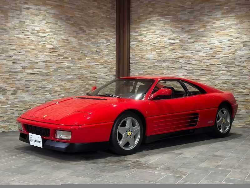 Red Ferrari sports car parked in front of a stone wall.