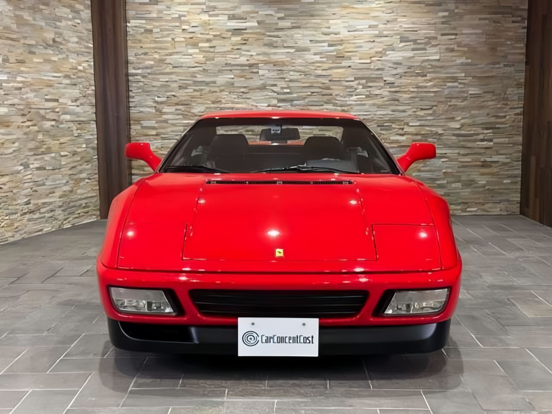 Red Ferrari sports car parked in front of a stone wall.