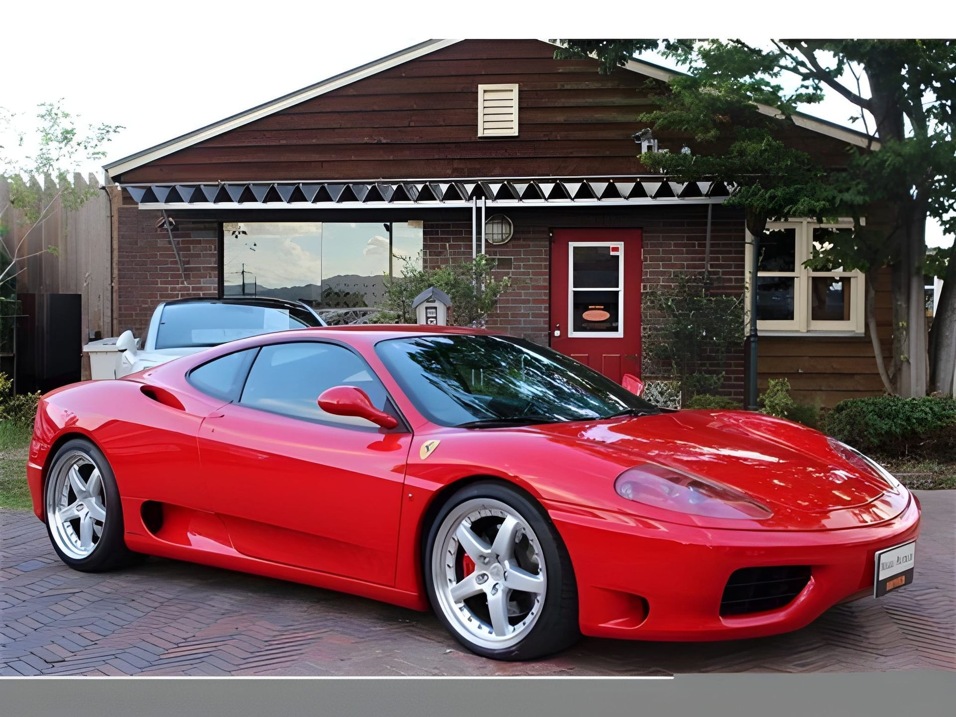 Red Ferrari sports car parked in front of other cars, likely a dealership.