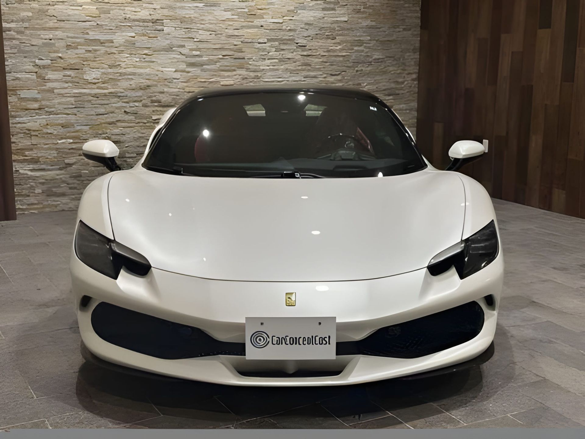 White Ferrari sports car parked in front of a stone wall.