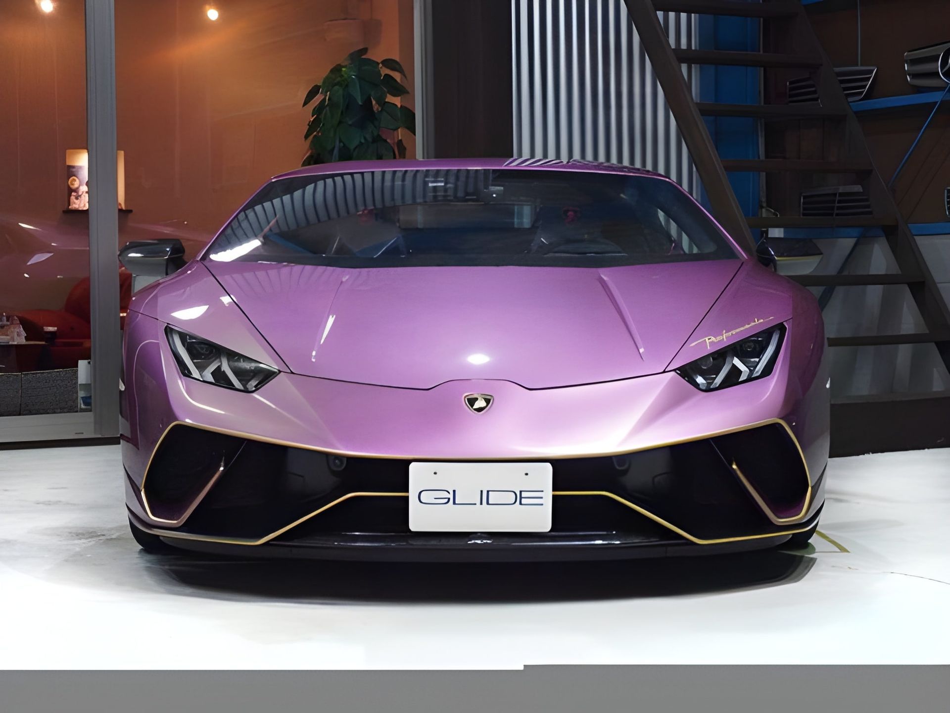 Pink Lamborghini Huracan with gold trim, parked inside a garage.