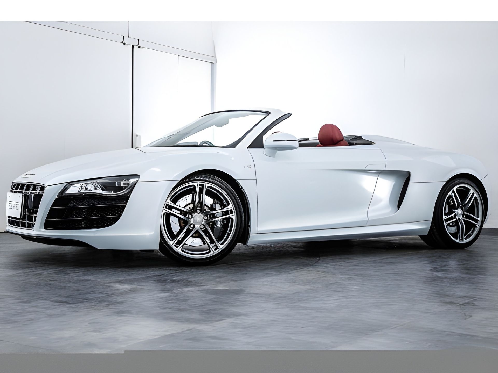 White Audi R8 Spyder convertible, front view. Black grille, brown interior.