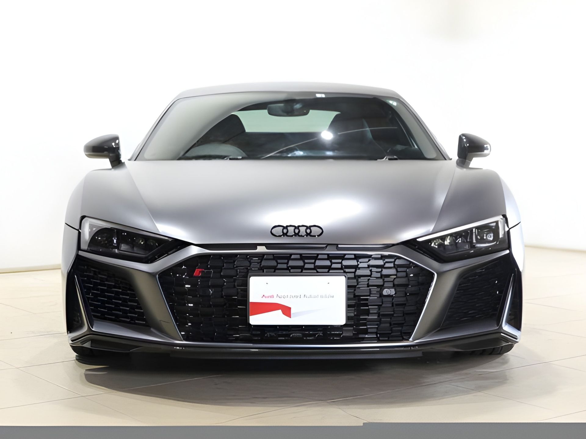 Gray Audi R8 sports car, front view, in a studio with a white background.
