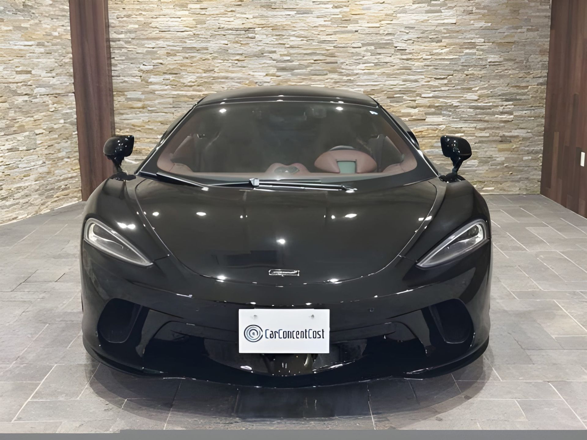 Black McLaren sports car parked indoors, facing the viewer.