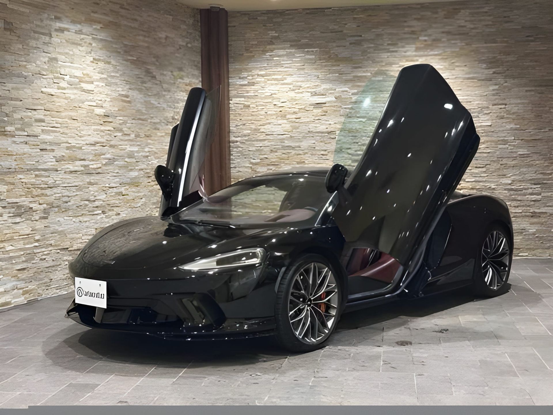 Black McLaren sports car parked indoors, facing the viewer.