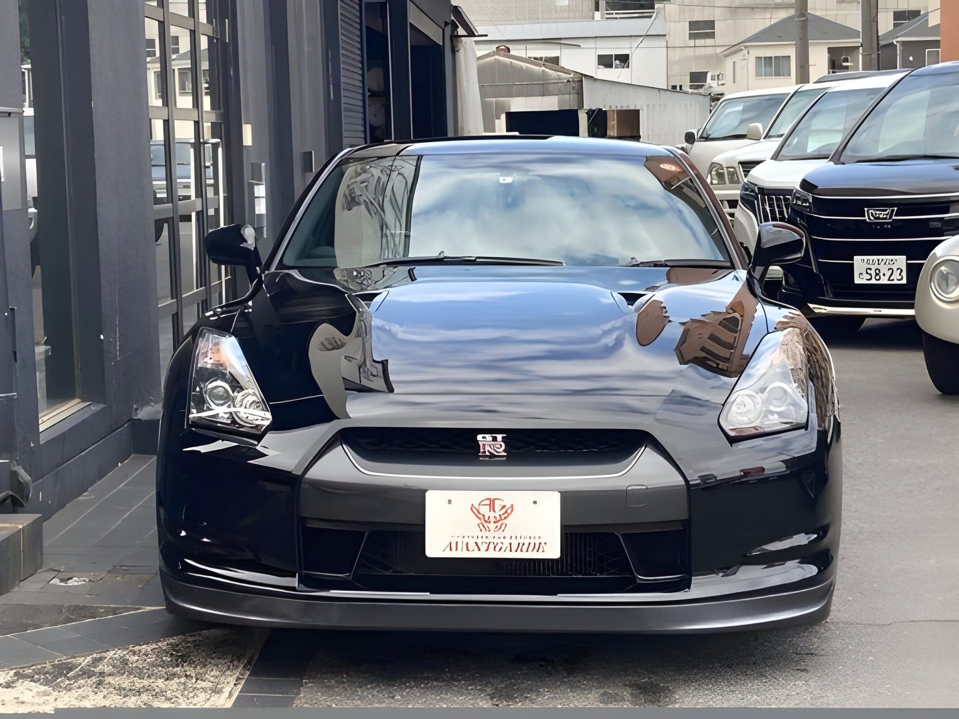 Black Nissan GT-R sports car parked in front of a building; front view showing hood scoop, grill, and headlights.