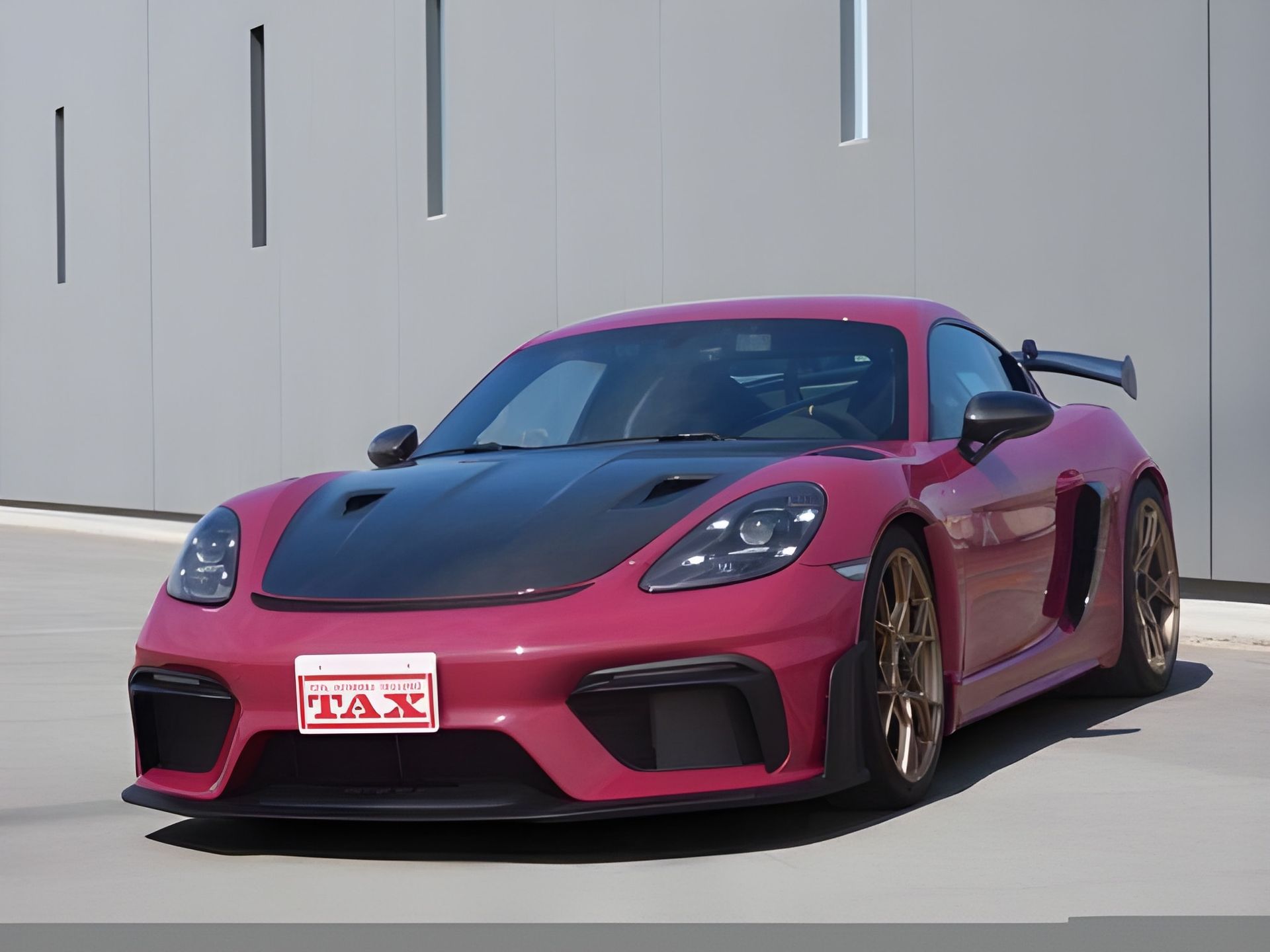 Pink Porsche sports car with black hood and black accents, license plate visible.