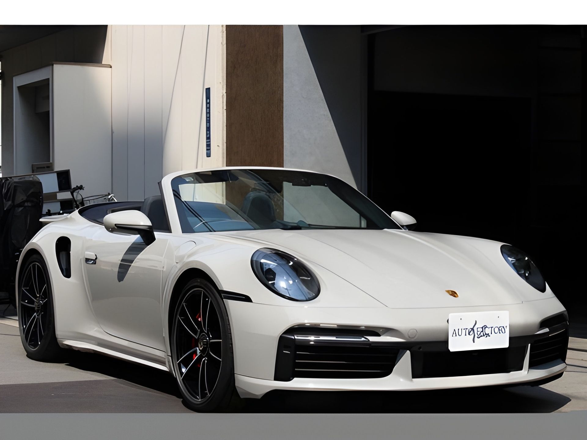 White Porsche 911 parked on a city street; front view with license plate