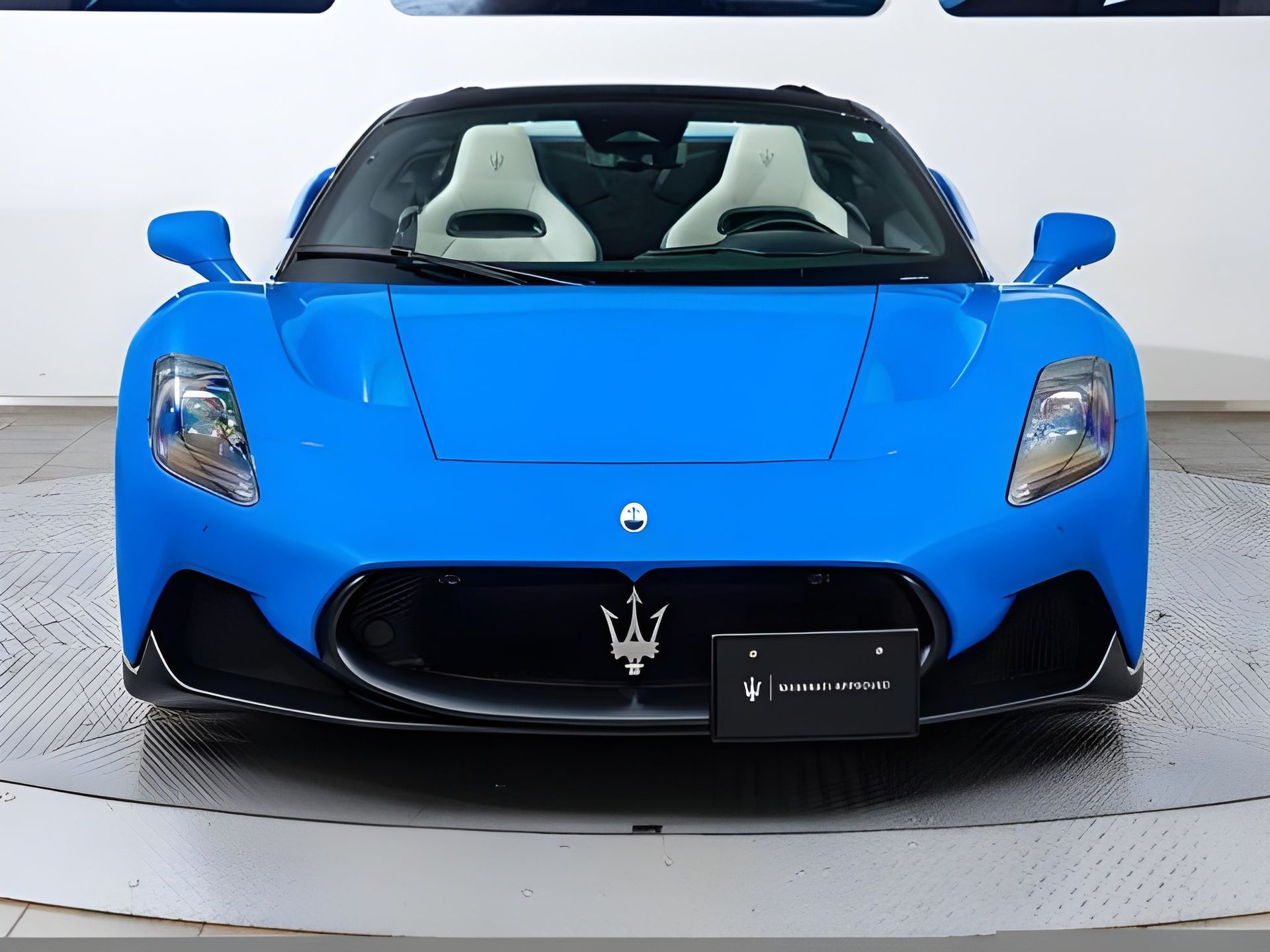 Blue Maserati MC20 convertible, front view, white interior, black accents.