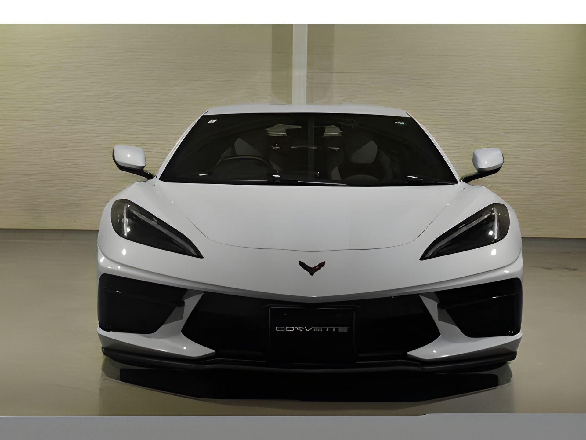 White Chevrolet Corvette sports car, front view. Black trim, indoors.