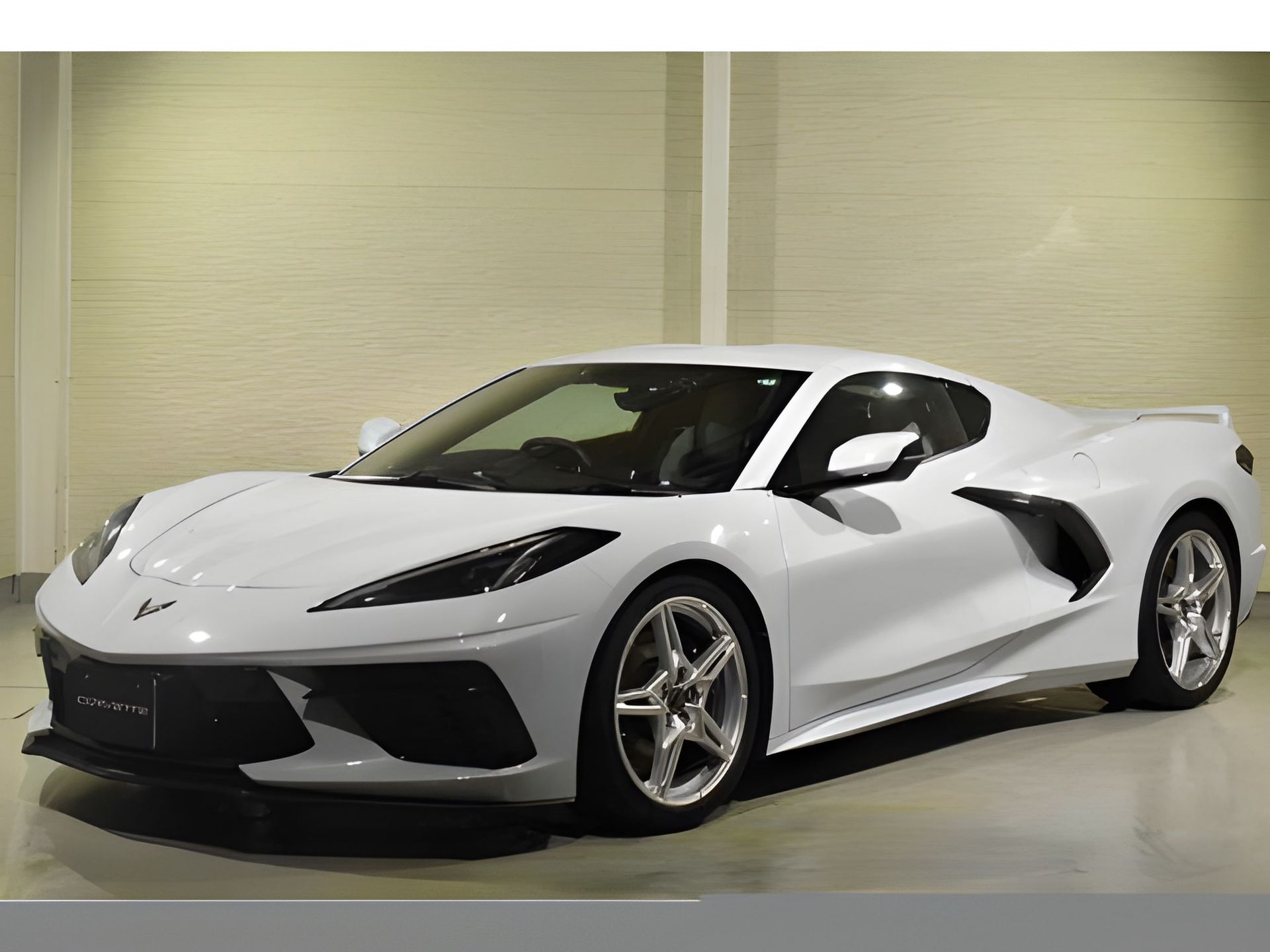 White Chevrolet Corvette sports car, front view. Black trim, indoors.