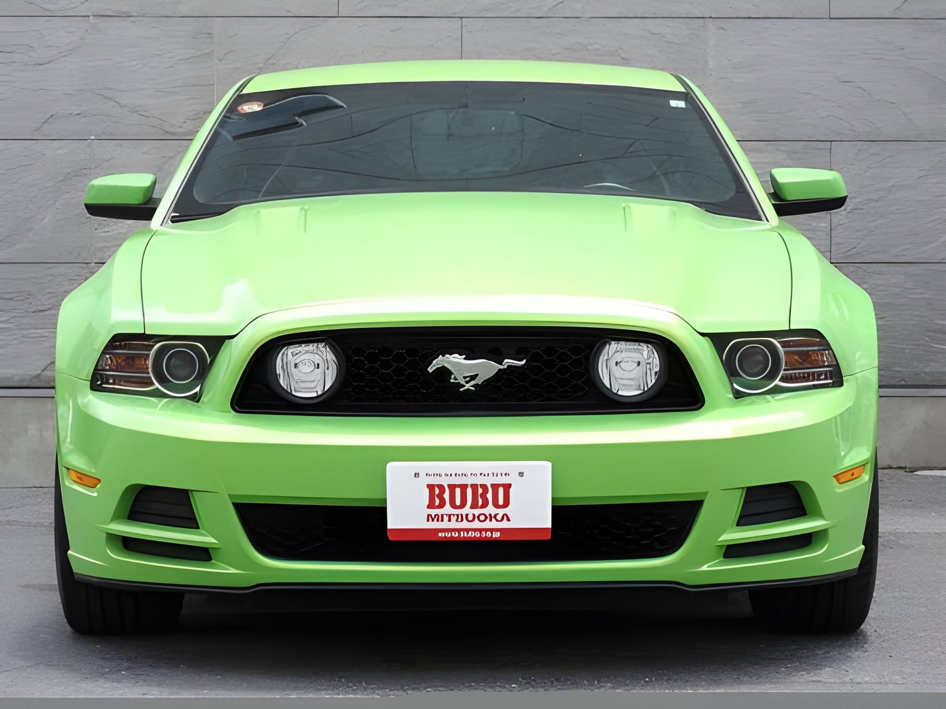 Green Ford Mustang with black grille and white license plate.