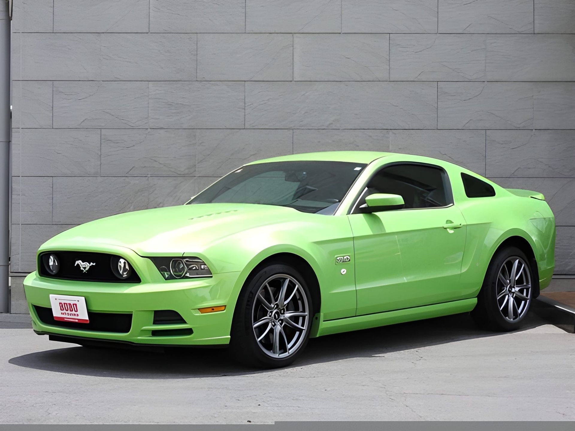 Green Ford Mustang with black grille and white license plate.