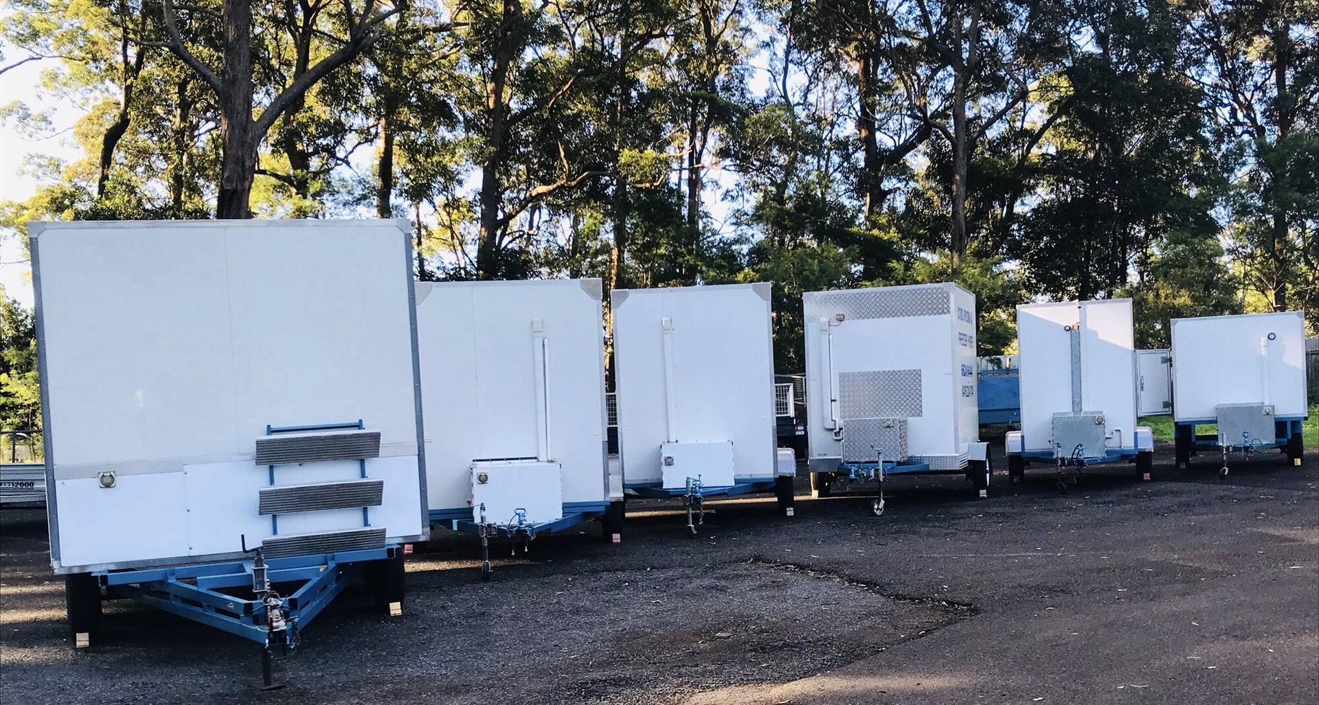 A Row of White Trailers are Parked in a Gravel lot - Cool Room in Lindendale, NSW