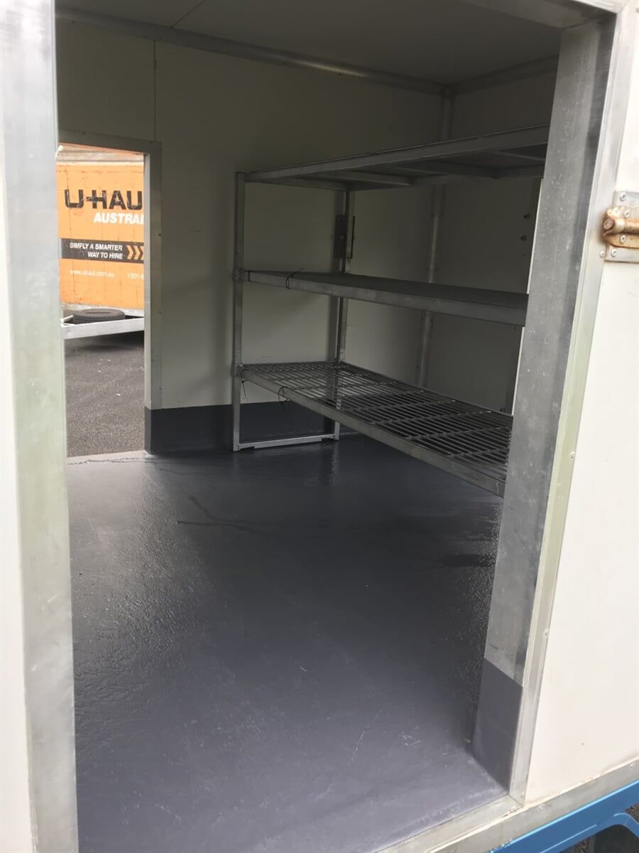 A Uhaul Truck is Parked in the Background of a Room with Shelves - Cool Room in Lindendale, NSW