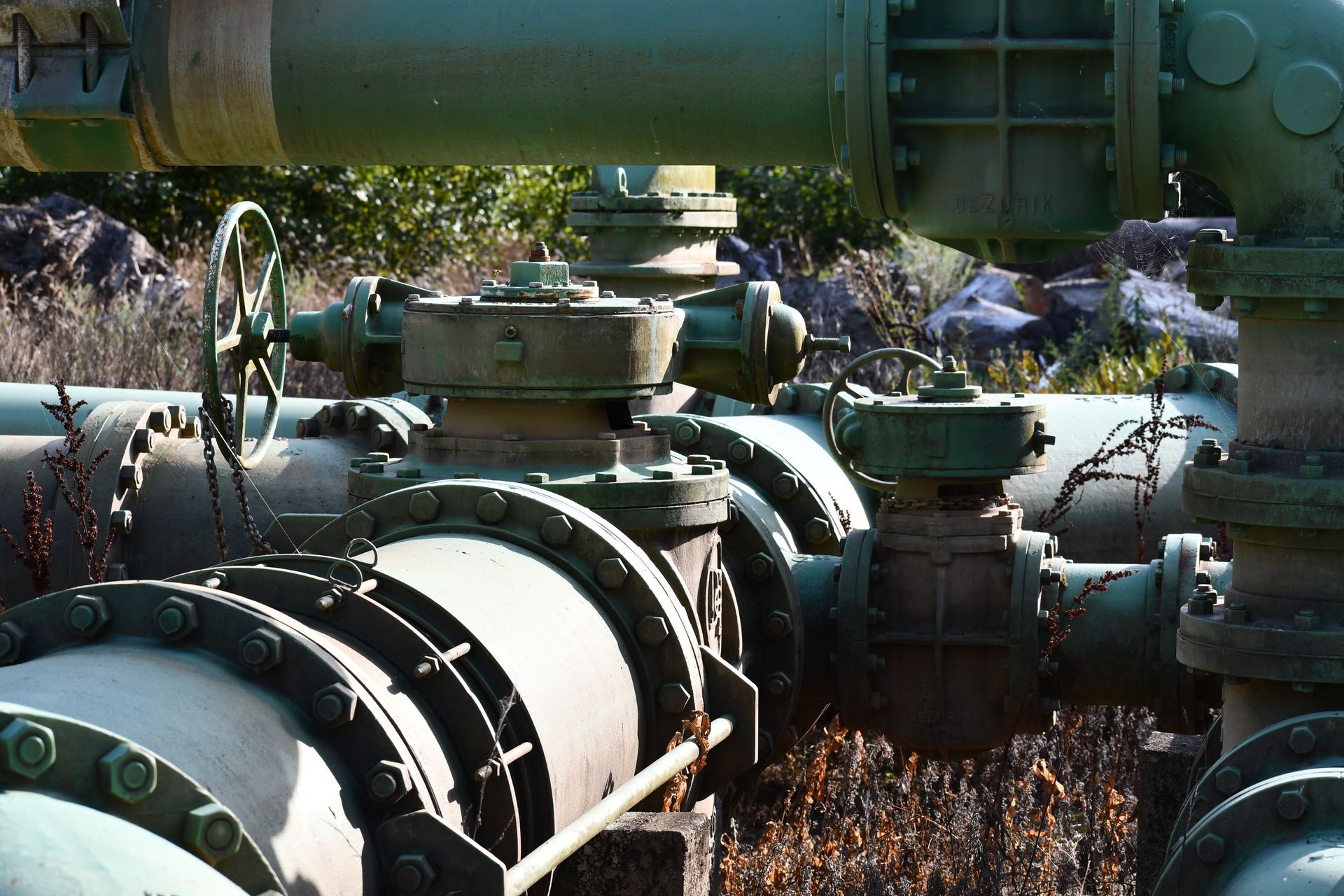 Industrial green pipelines and valves in an outdoor utility system infrastructure for water supply.