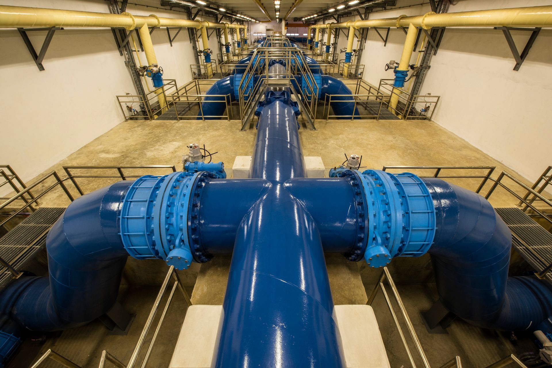 Large industrial water pumping system with blue pipes and valves inside modern facility.