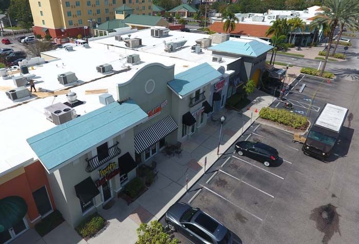 An aerial view of a shopping center with a white roof