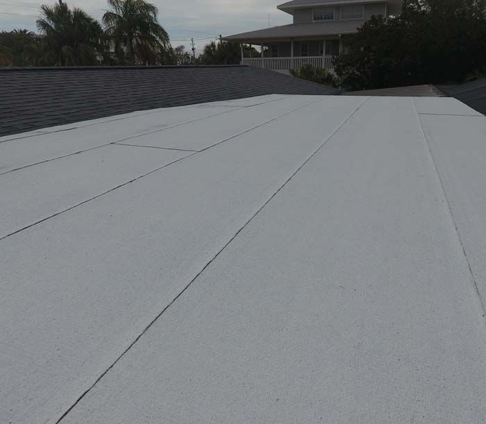A white roof with a house in the background.