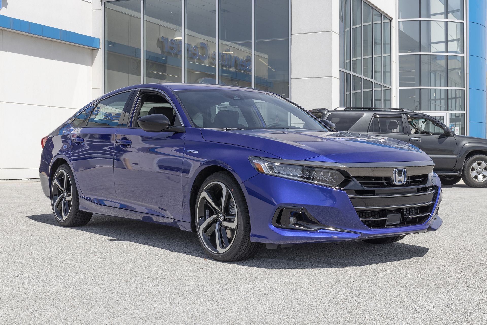 Blue Honda sedan parked outside a modern dealership building