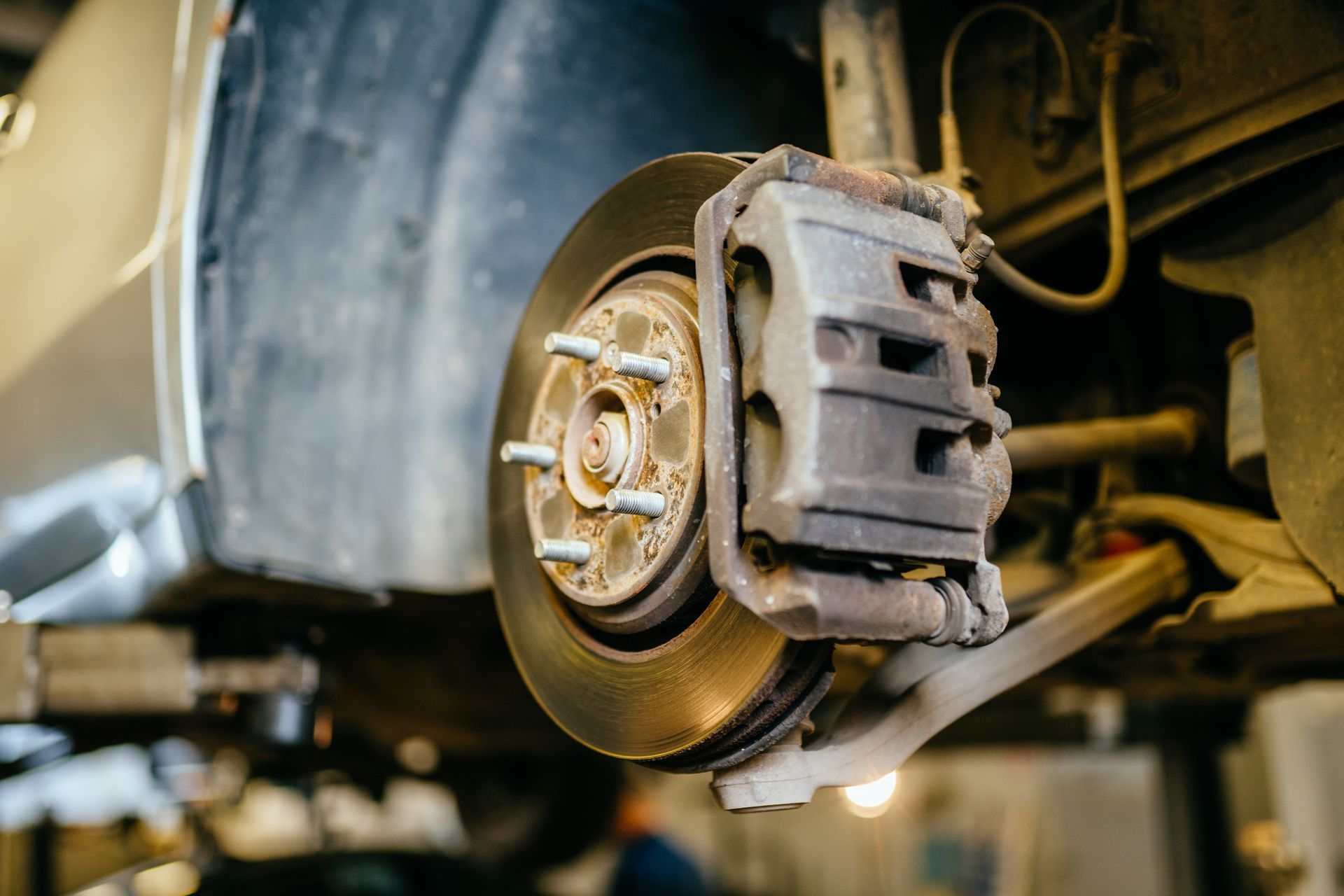 Close-up of a car brake rotor and caliper inside a wheel well during maintenance