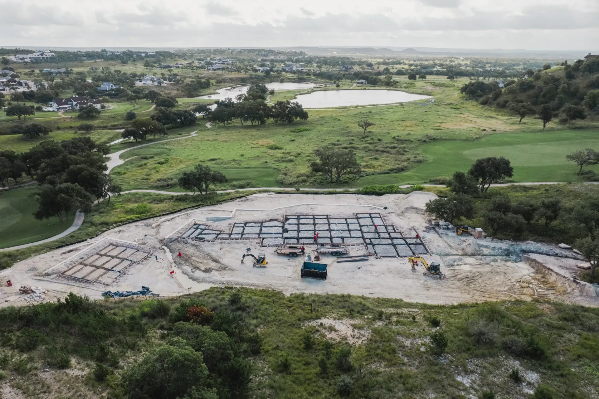 An aerial view of a construction site with a golf course in the background.