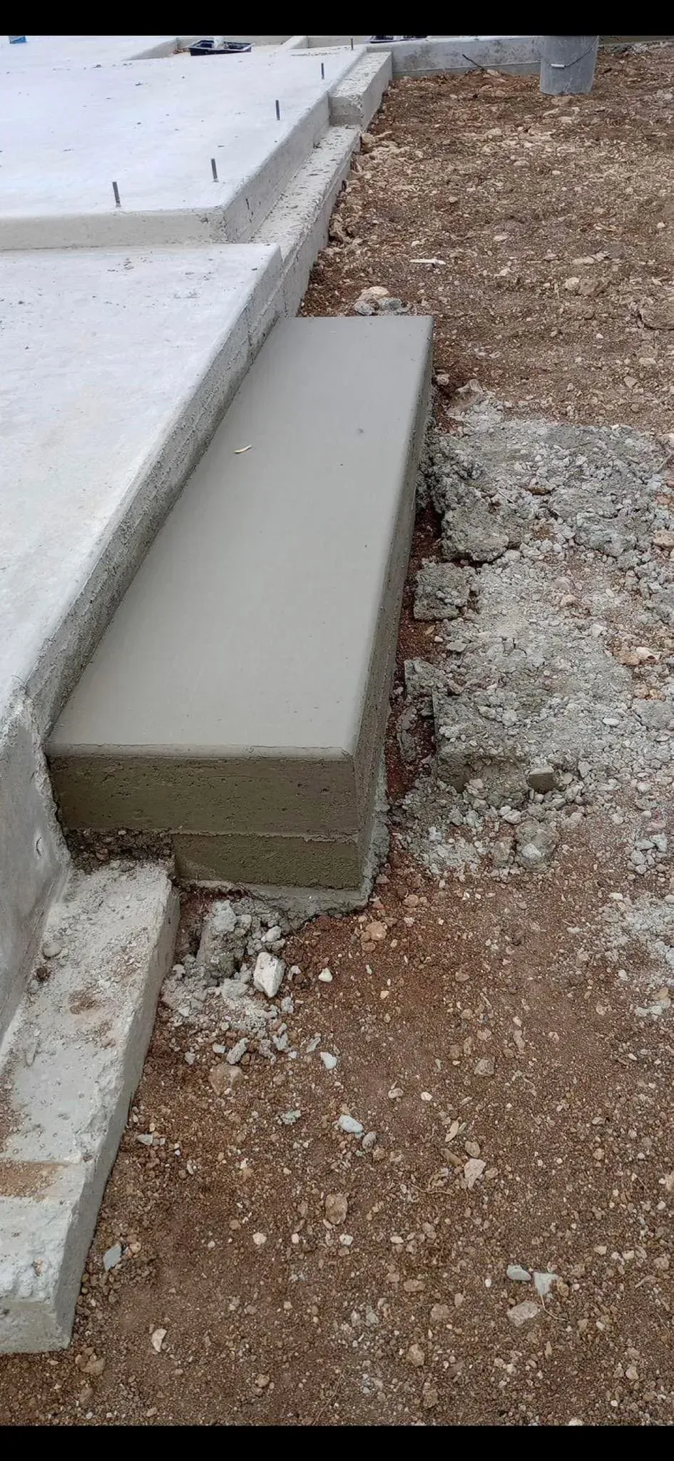 A concrete block is sitting on the ground next to a concrete staircase.
