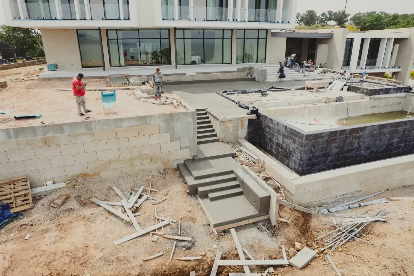 A man in a red shirt is standing in front of a building under construction.