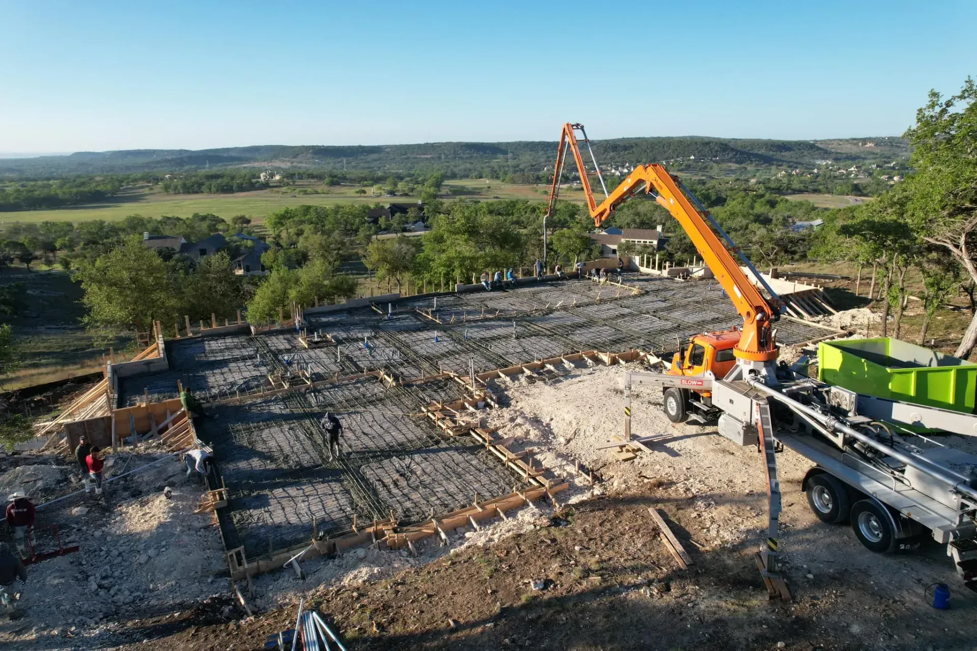 An aerial view of a construction site with a crane pumping concrete.