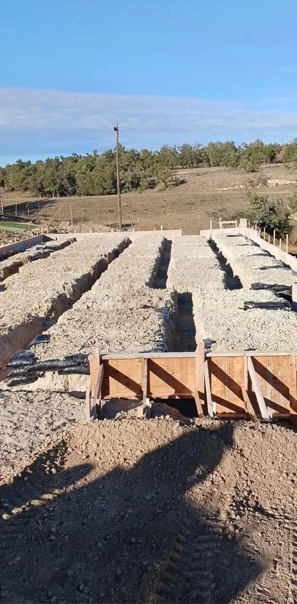 A construction site with a lot of dirt and trees in the background.