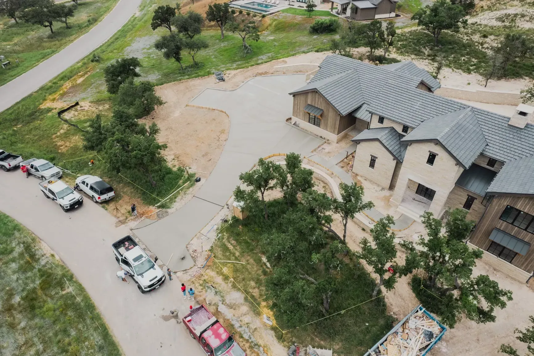 An aerial view of a house under construction with trucks parked in front of it.
