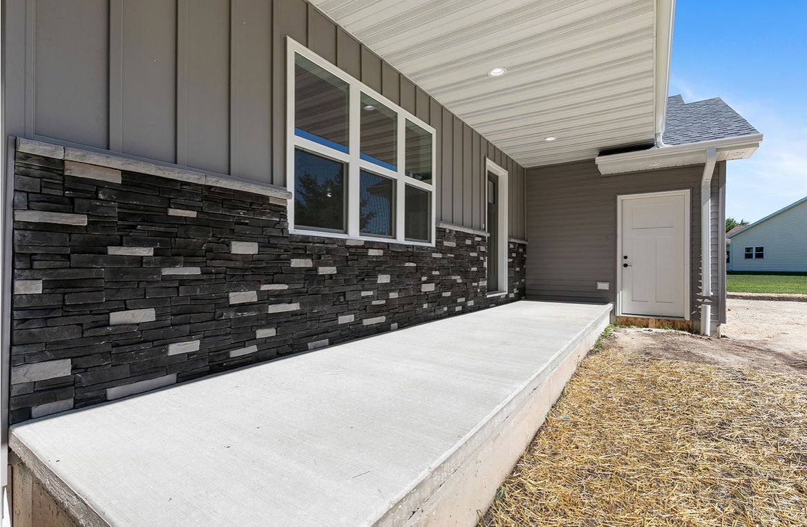 Woman in straw hat smiles, holding wine glass near a lake.