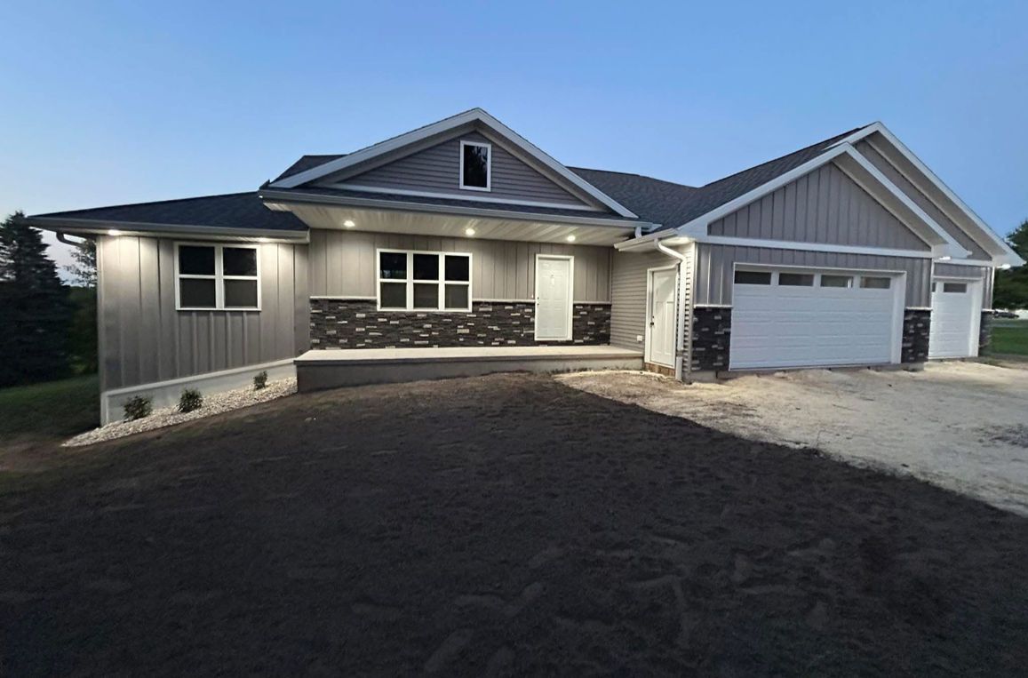 Woman in straw hat smiles, holding wine glass near a lake.