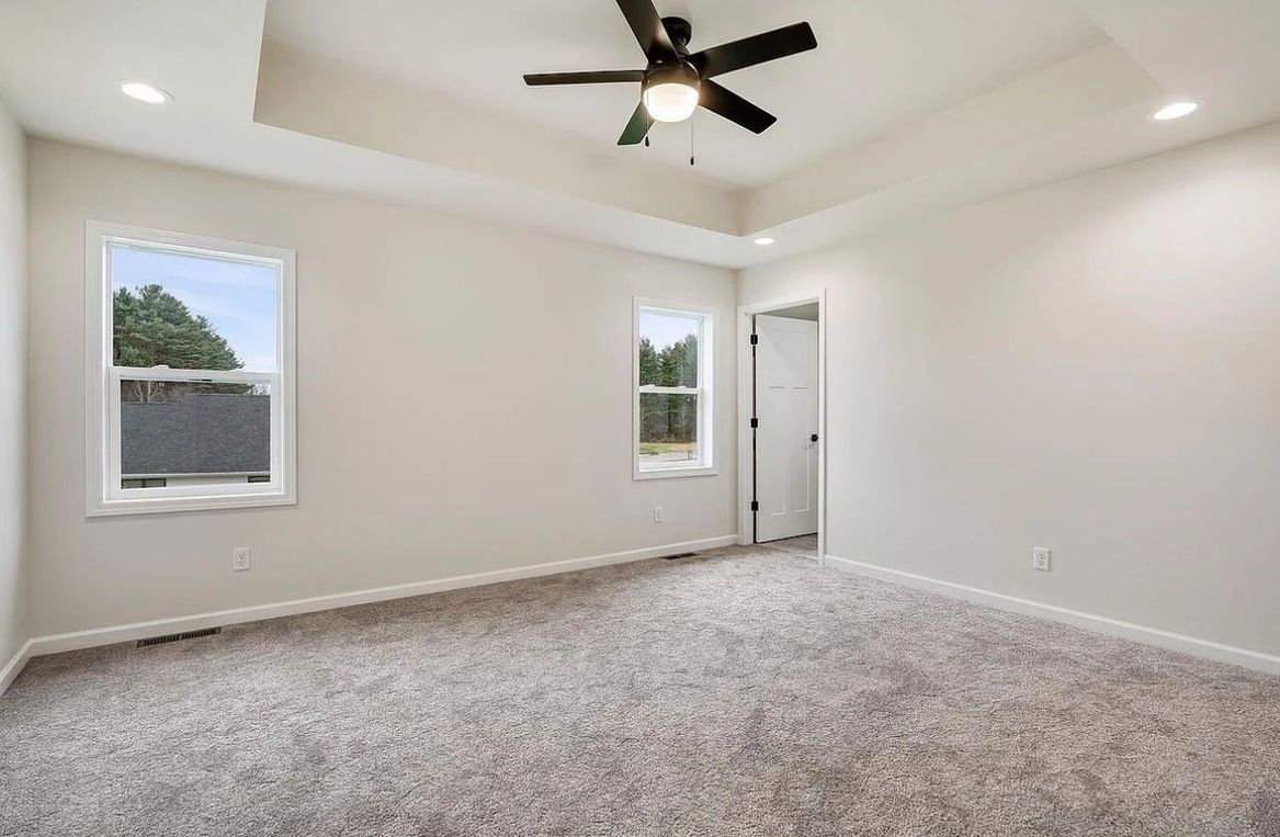Woman in straw hat smiles, holding wine glass near a lake.