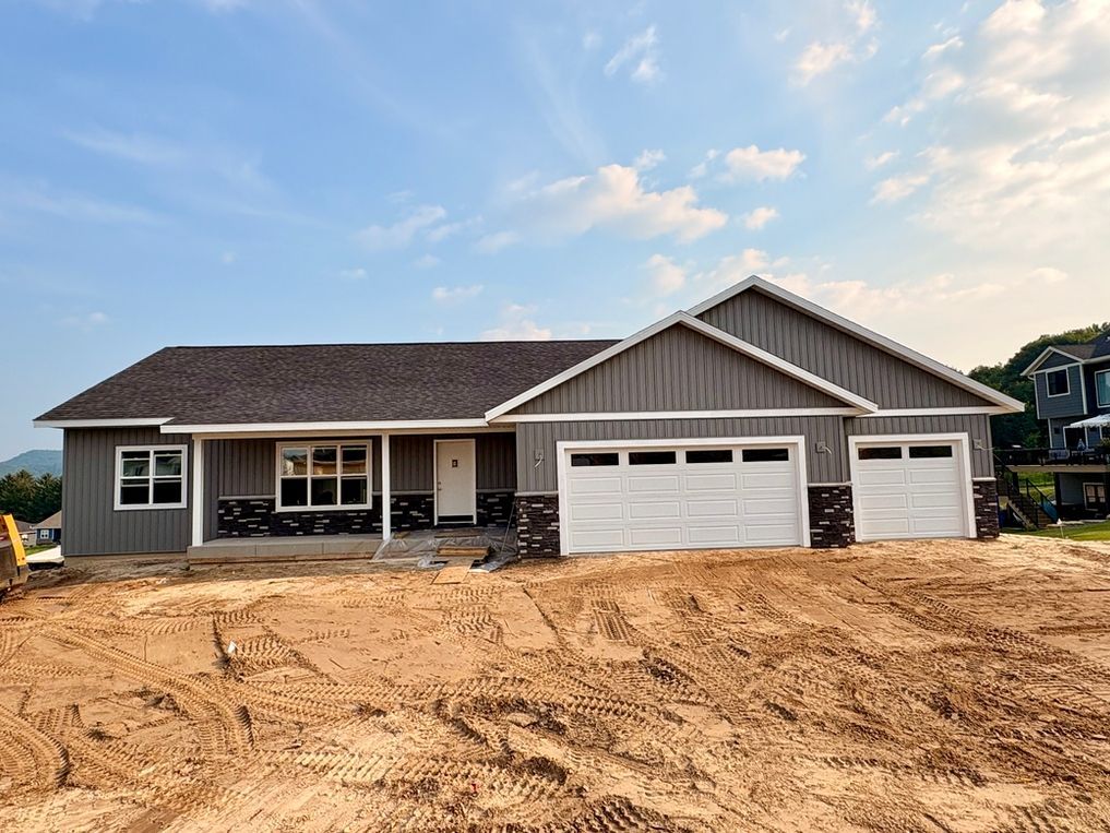 Woman in straw hat smiles, holding wine glass near a lake.