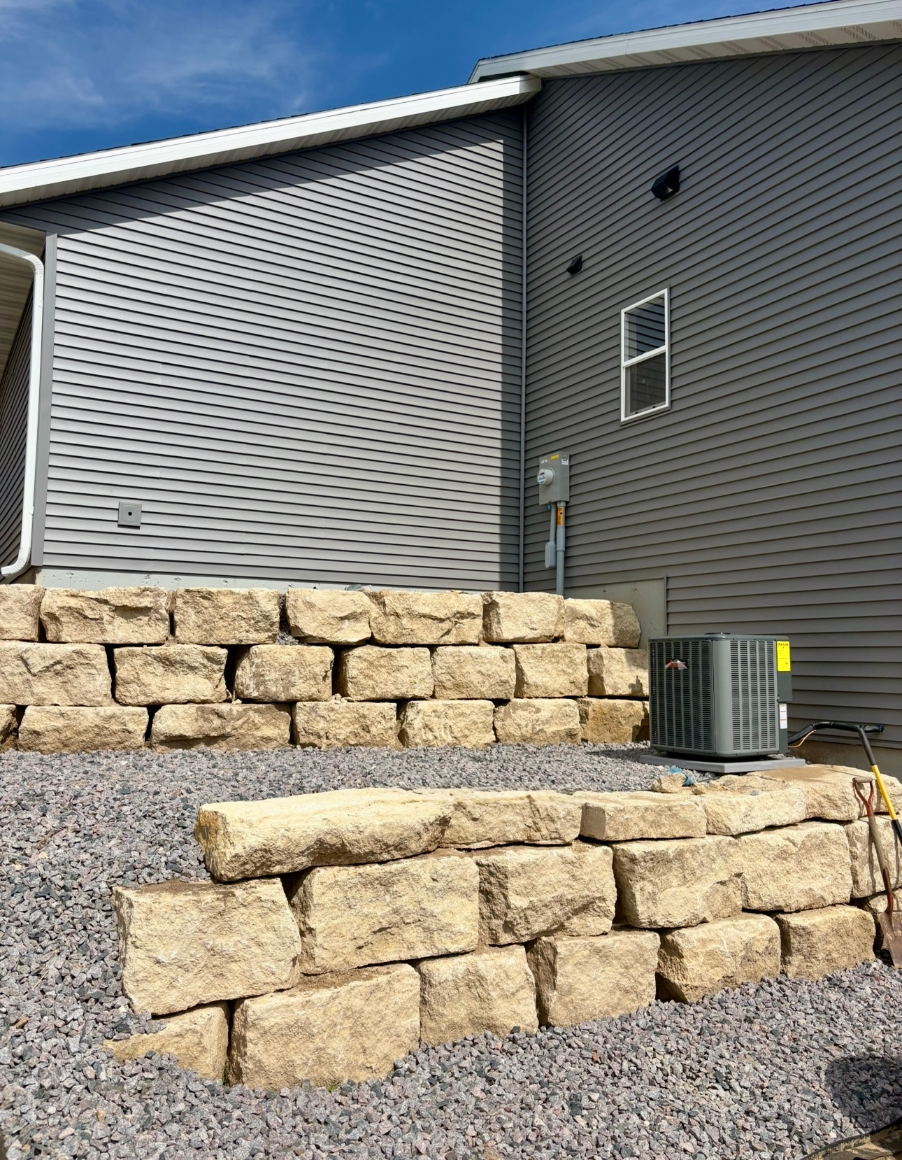 Woman in straw hat smiles, holding wine glass near a lake.