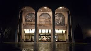 A large building with arches and paintings on the windows is lit up at night.