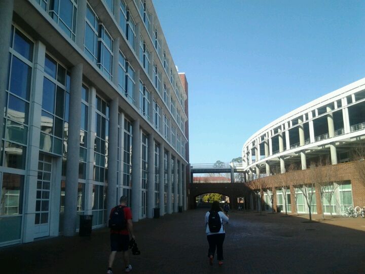 Two people walking in front of a building with lots of windows