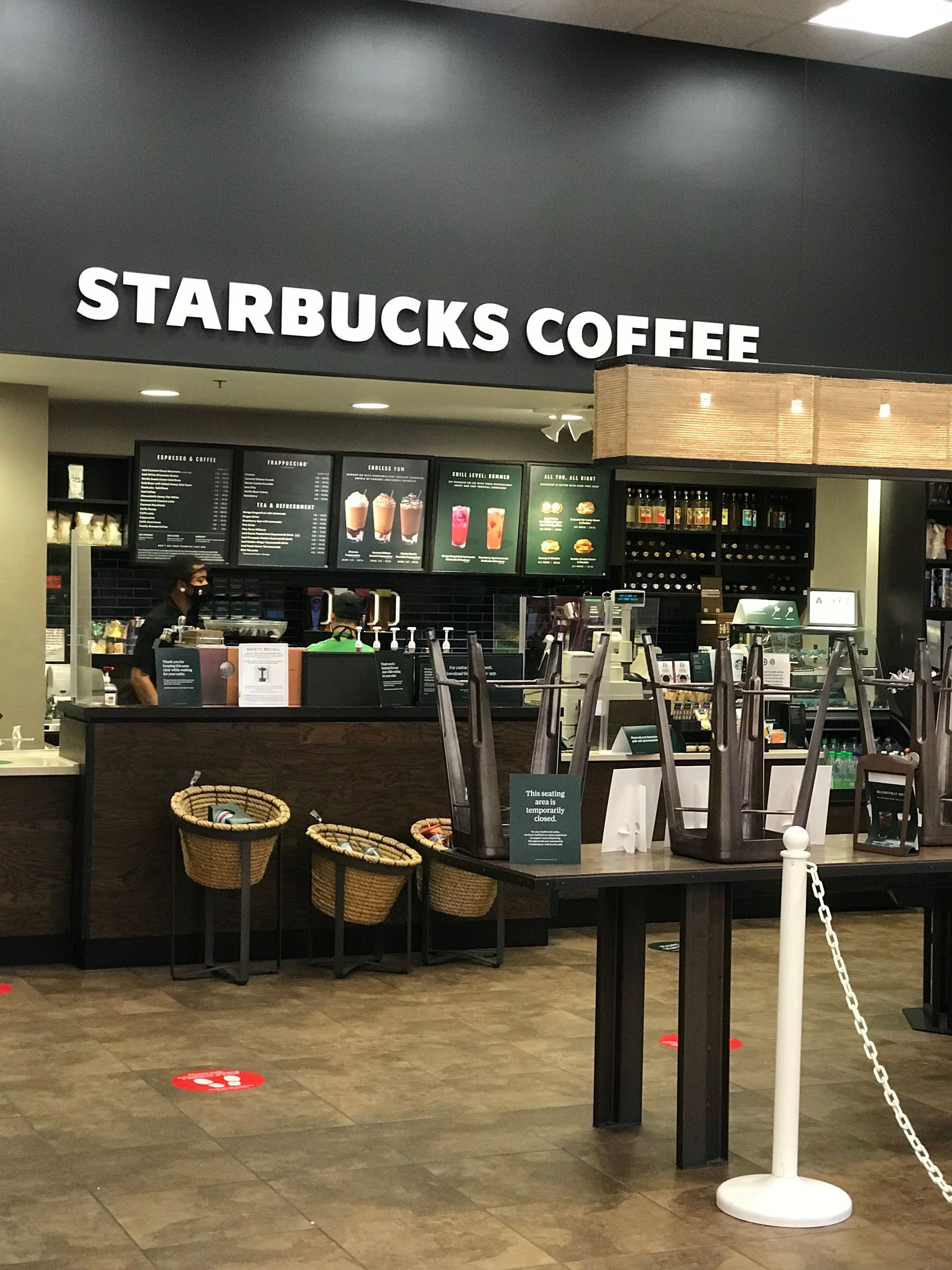 The inside of a starbucks coffee shop with tables and chairs empty