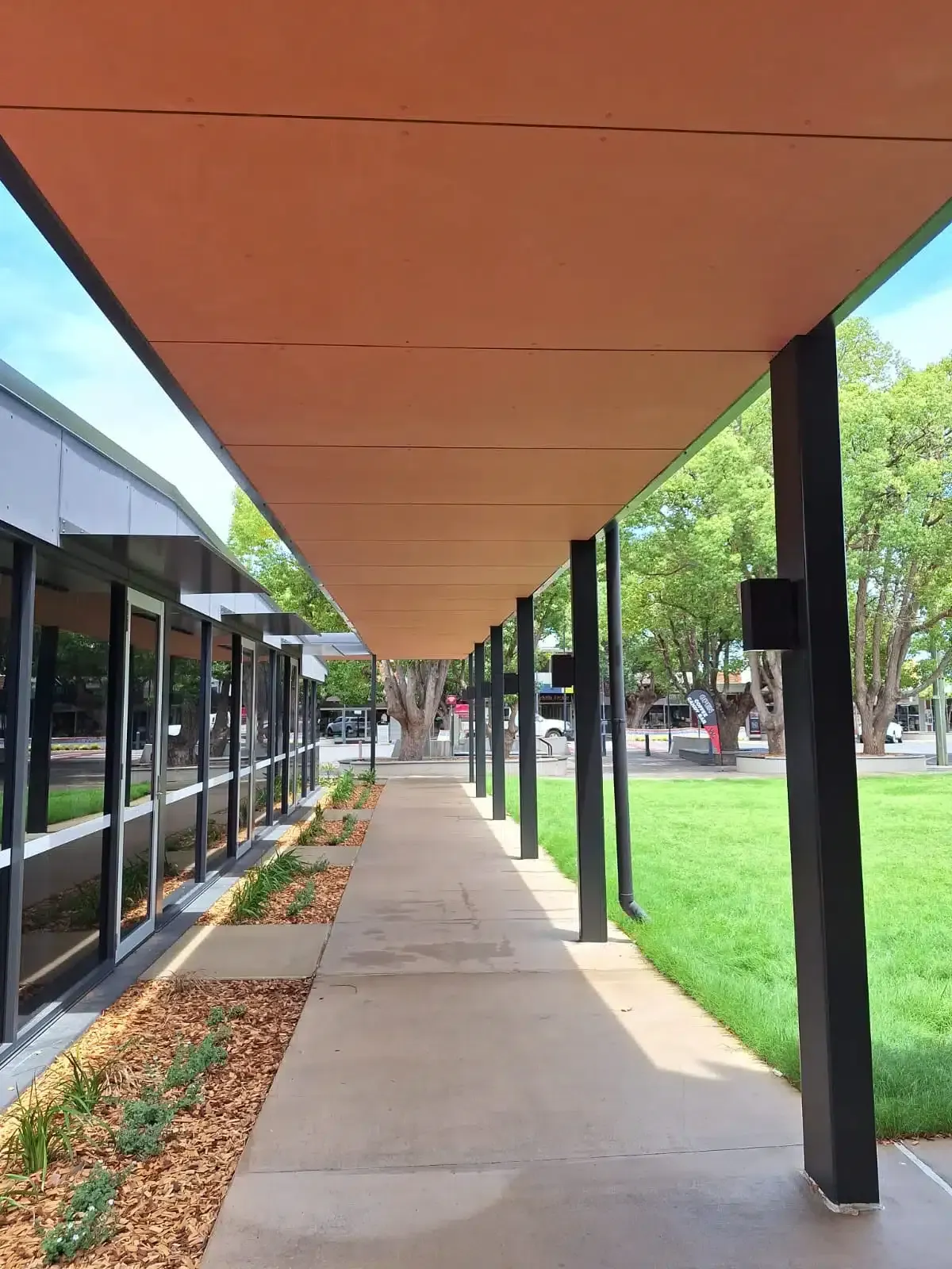 A Covered Walkway Between Two Buildings With Trees in the Background — Siash Construction Group in Elliot Heads, QLD