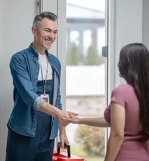 A Man is Shaking Hands With a Woman in a Doorway — Siash Construction Group in Gooburrum, QLD