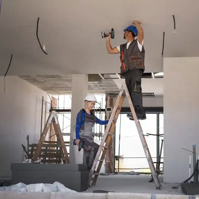 A Man is Standing on a Ladder Working on a Ceiling — Siash Construction Group in Gooburrum, QLD