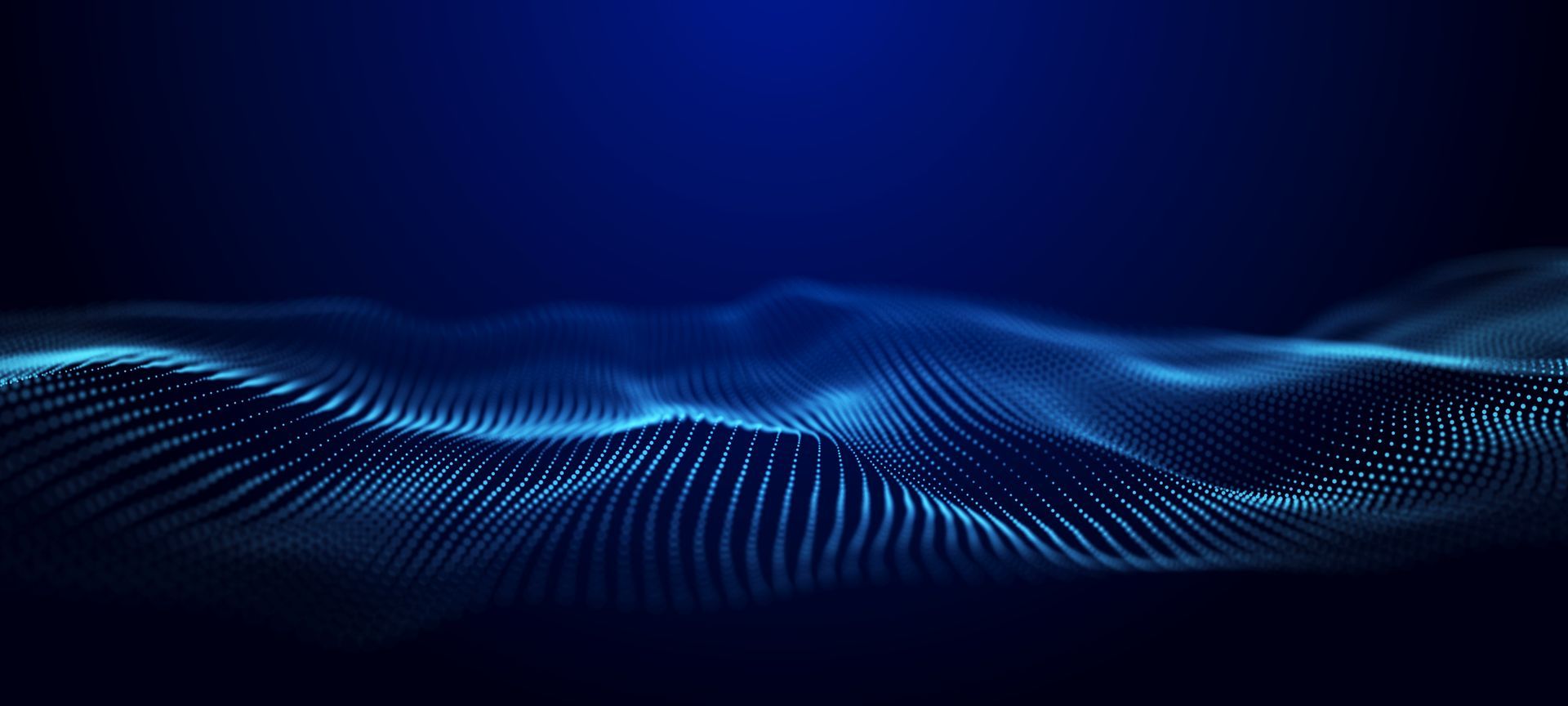 Woman in headset smiles at a computer, assisted by a person leaning over her shoulder in an office setting.