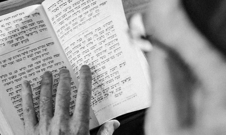 Rabbi reading from a Torah at a Jewish funeral service
