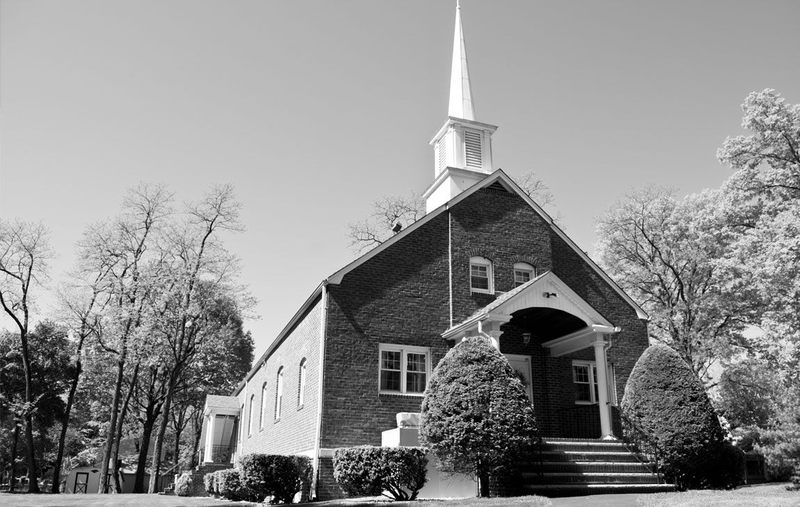 A brick Temple of The Church of Jesus Christ of Latter-day Saints with a white steeple.